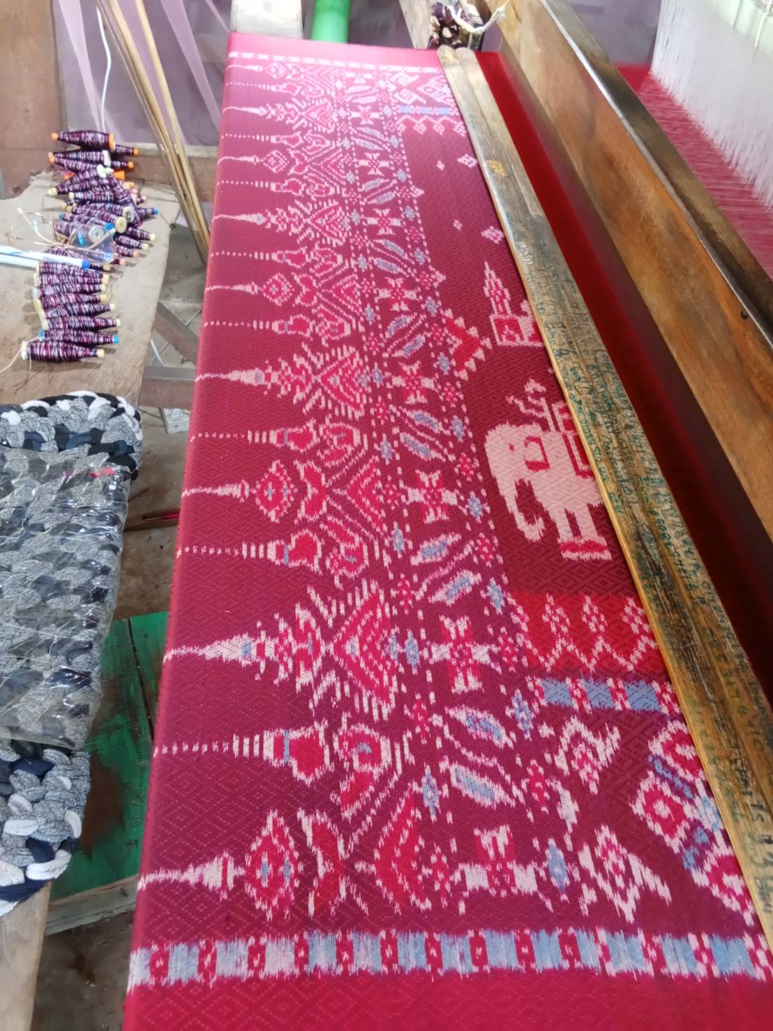 ผ้าไหมมัดหมี่ยกดอก 5ตะกอ มีหน้านาง ขนาด 1x2เมตร สีแดง ลายปราสาท ช้าง จากกี่บ้านคุณยายฐิสดา