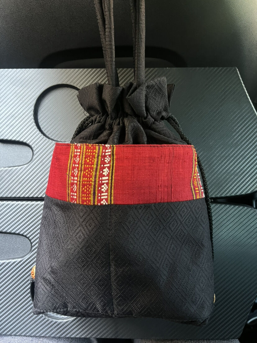 กระเป๋าผ้าไหม มีหูรูด ขนาด 18x20ซม. หูกระเป๋าสูง 13ซม. พื้นสีดำแต่งผ้าไหมขิดสีแดง รหัส GLA-ME-1115681